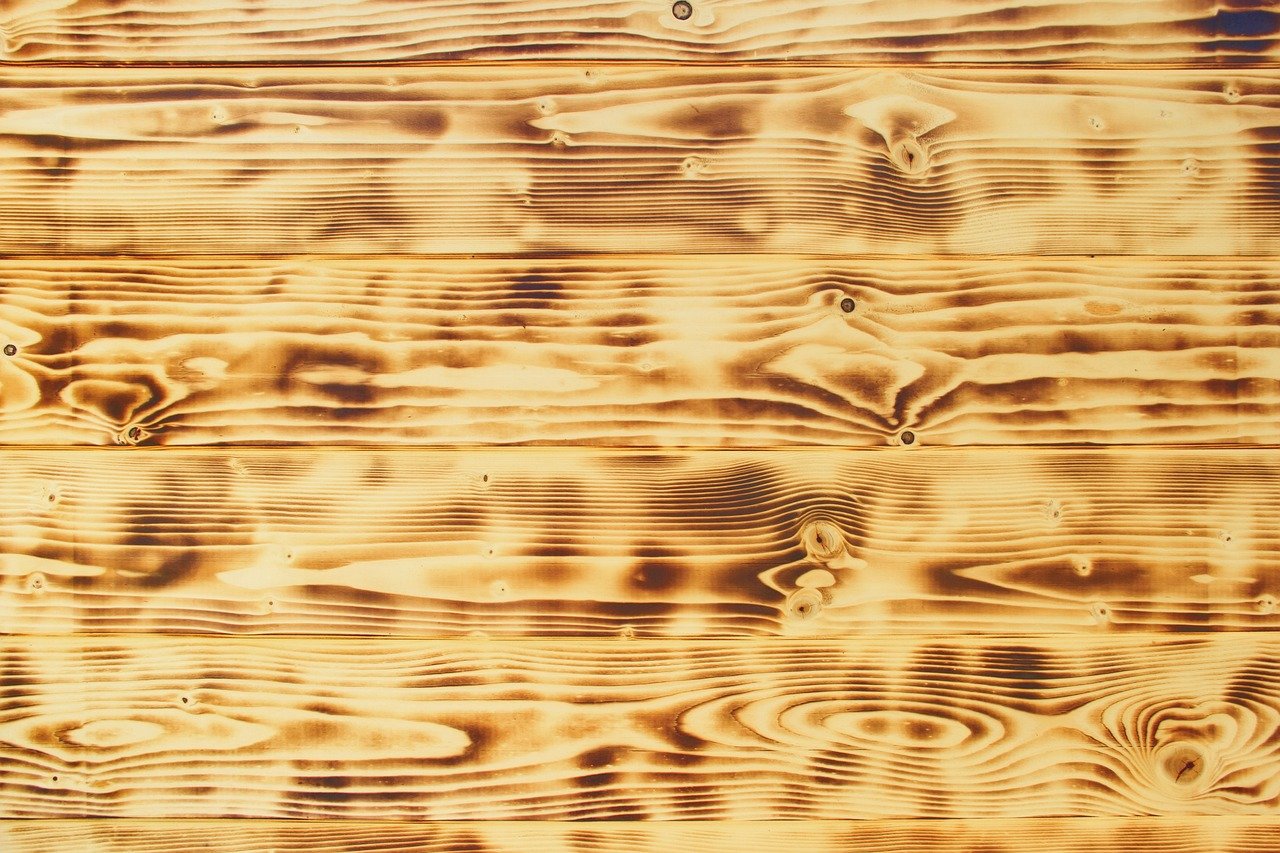 Detalhe em close-up de uma mesa lateral ou console em madeira burl, mostrando o grão ondulado e marmorizado