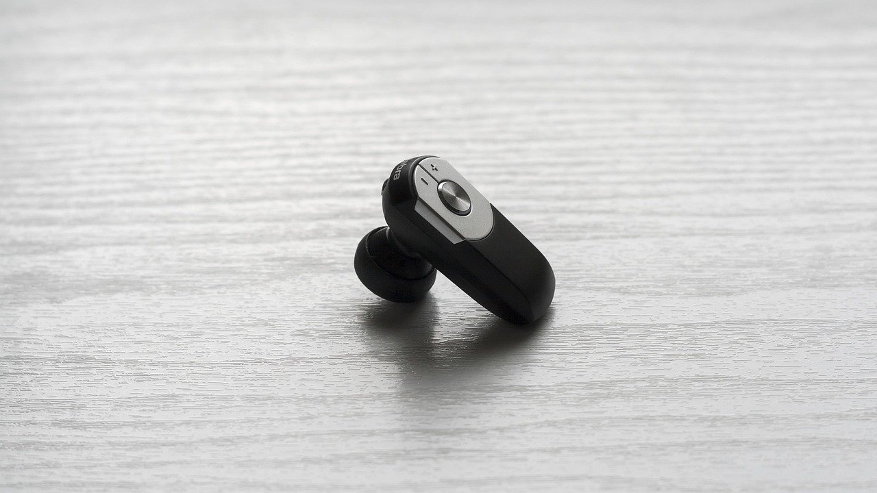 transmissor bluetooth pequeno conectado à entrada de fone de ouvido de uma tela de encosto de assento de avião, fones de ouvido sem fio ao lado