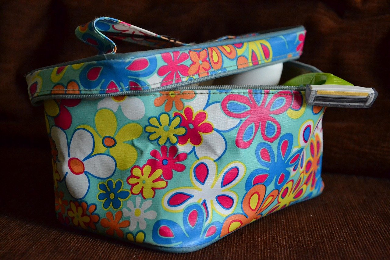 necessaire de viagem pendurada em uma barra de chuveiro ou toalheiro de banheiro de hotel, compartimentos abertos mostrando produtos de higiene organizados