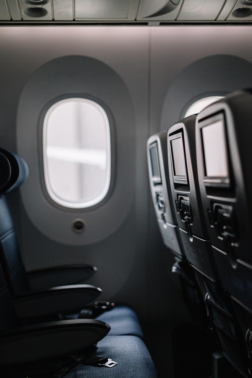 hammock/rede pequena de tecido presa embaixo de uma mesinha de avião, com pés apoiados dentro dela