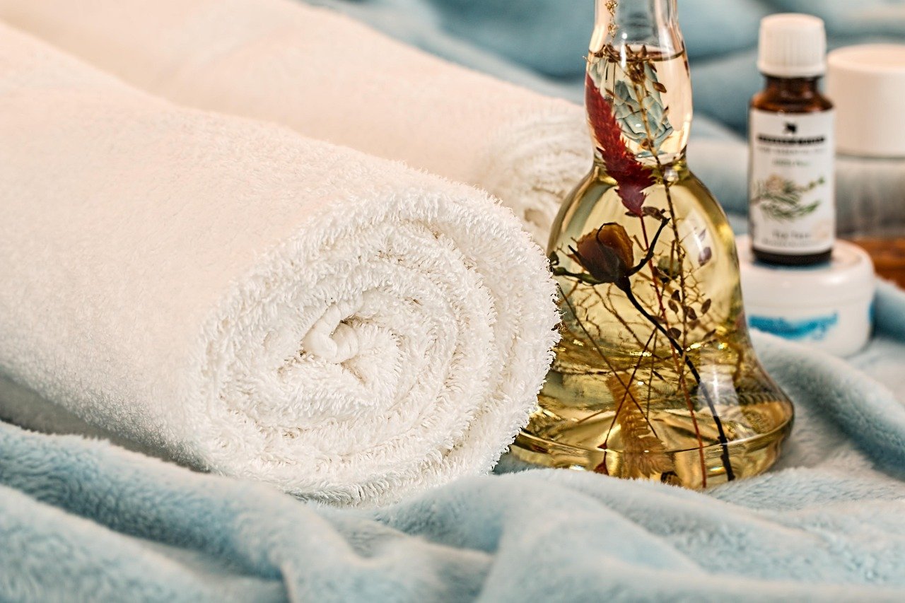 Skincare bottles and rolled towels arranged spa-style
