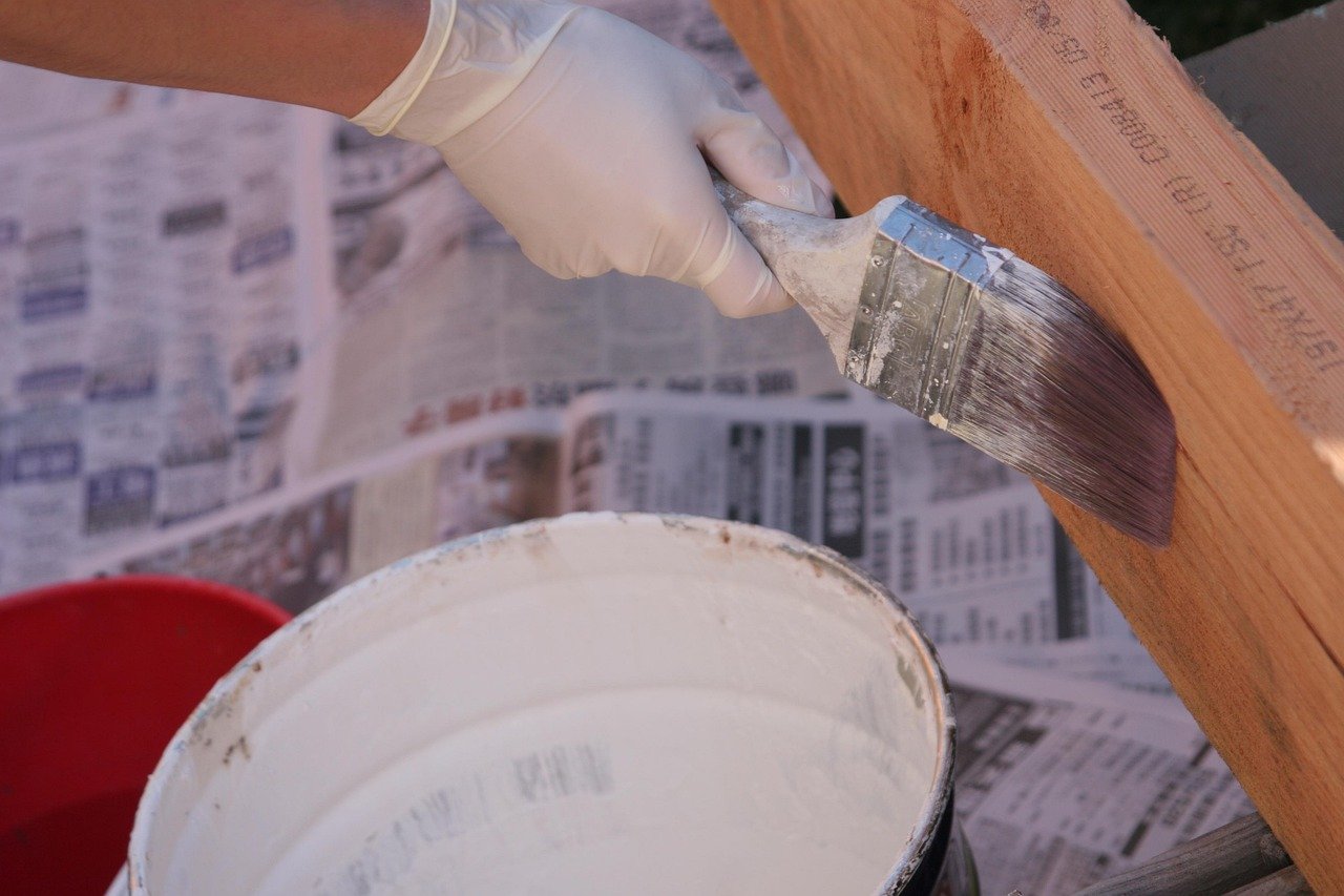 Gloved hands applying material to a wood surface during a DIY project