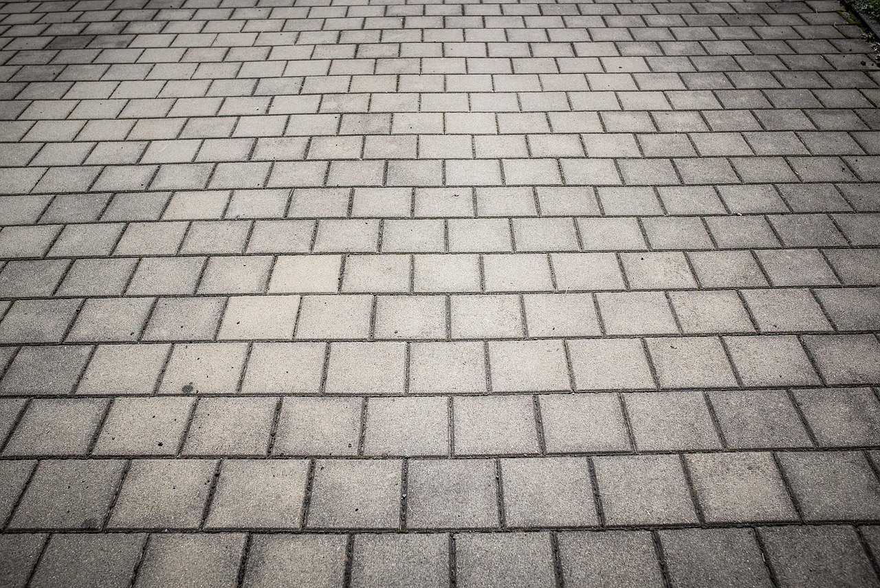 Paver stones being laid in a patterned patio installation