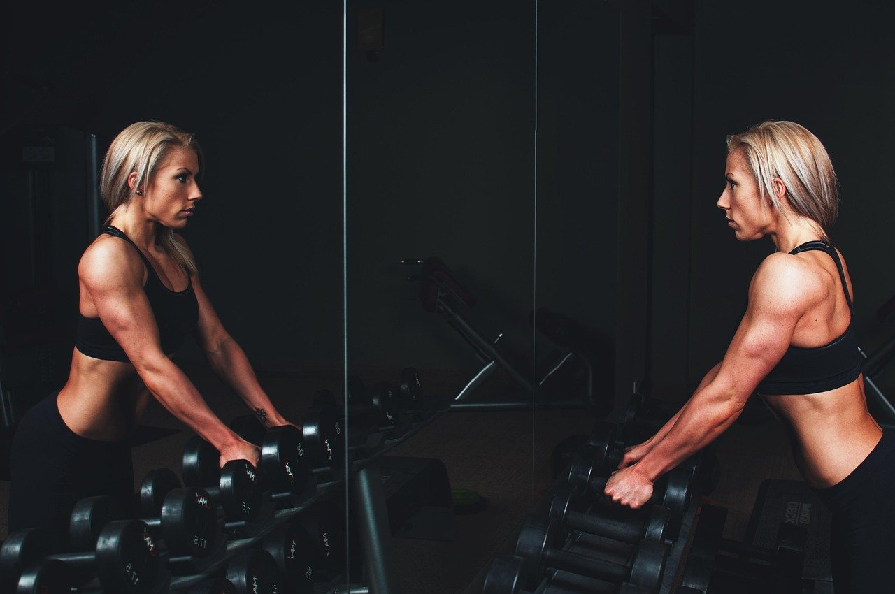 Full wall mirror reflecting a home gym workout