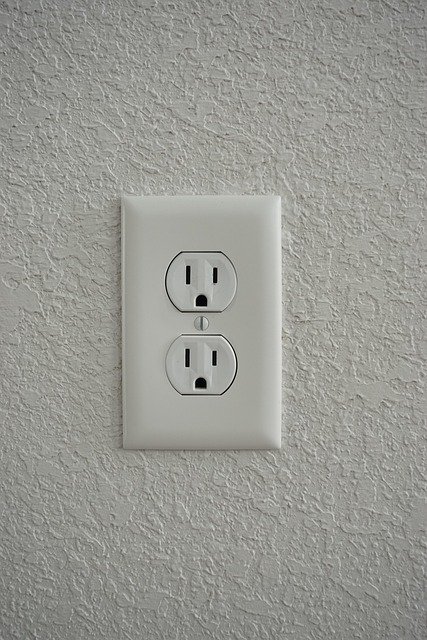 Close-up of a charger cable plugged into a wall outlet