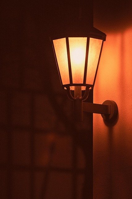 Wall sconces mounted on both sides of a bed